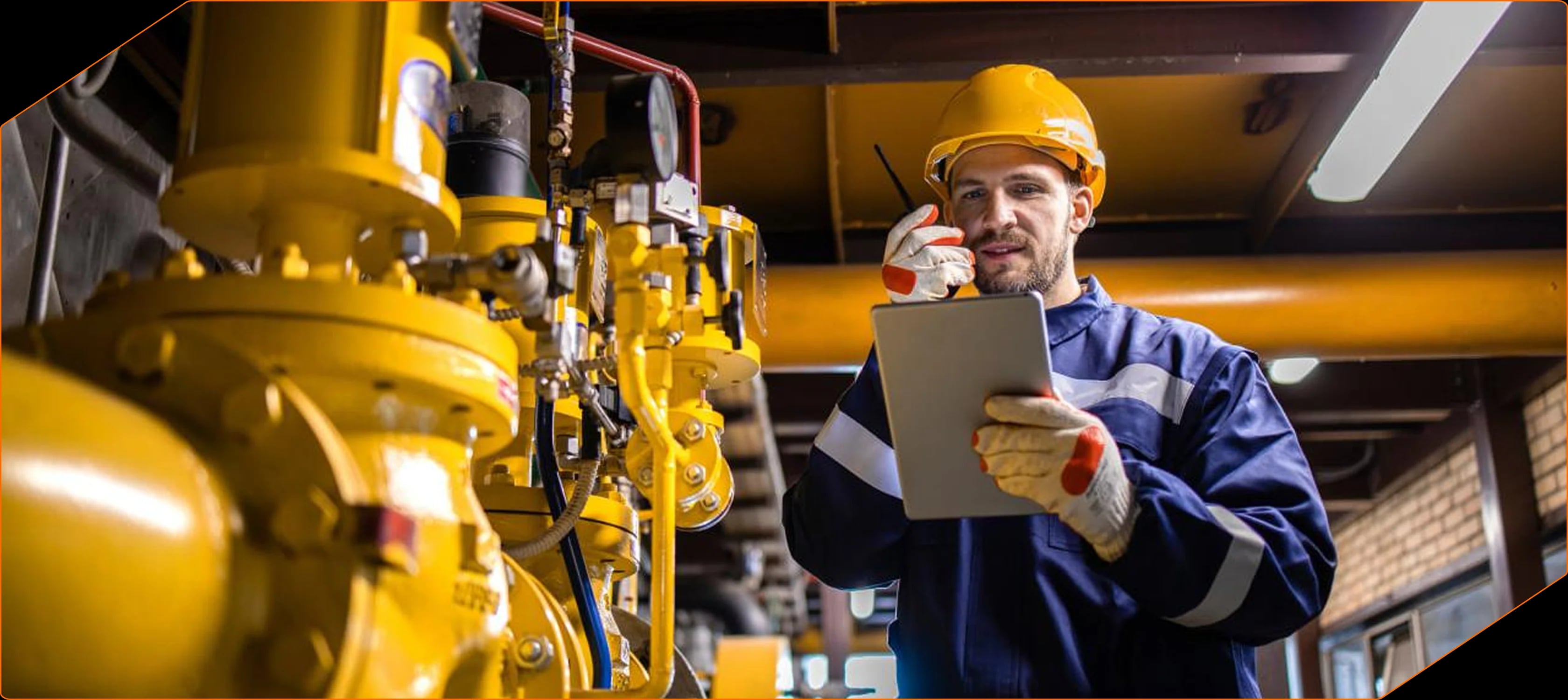 Engineer in a hard hat with a tablet beside yellow process equipment