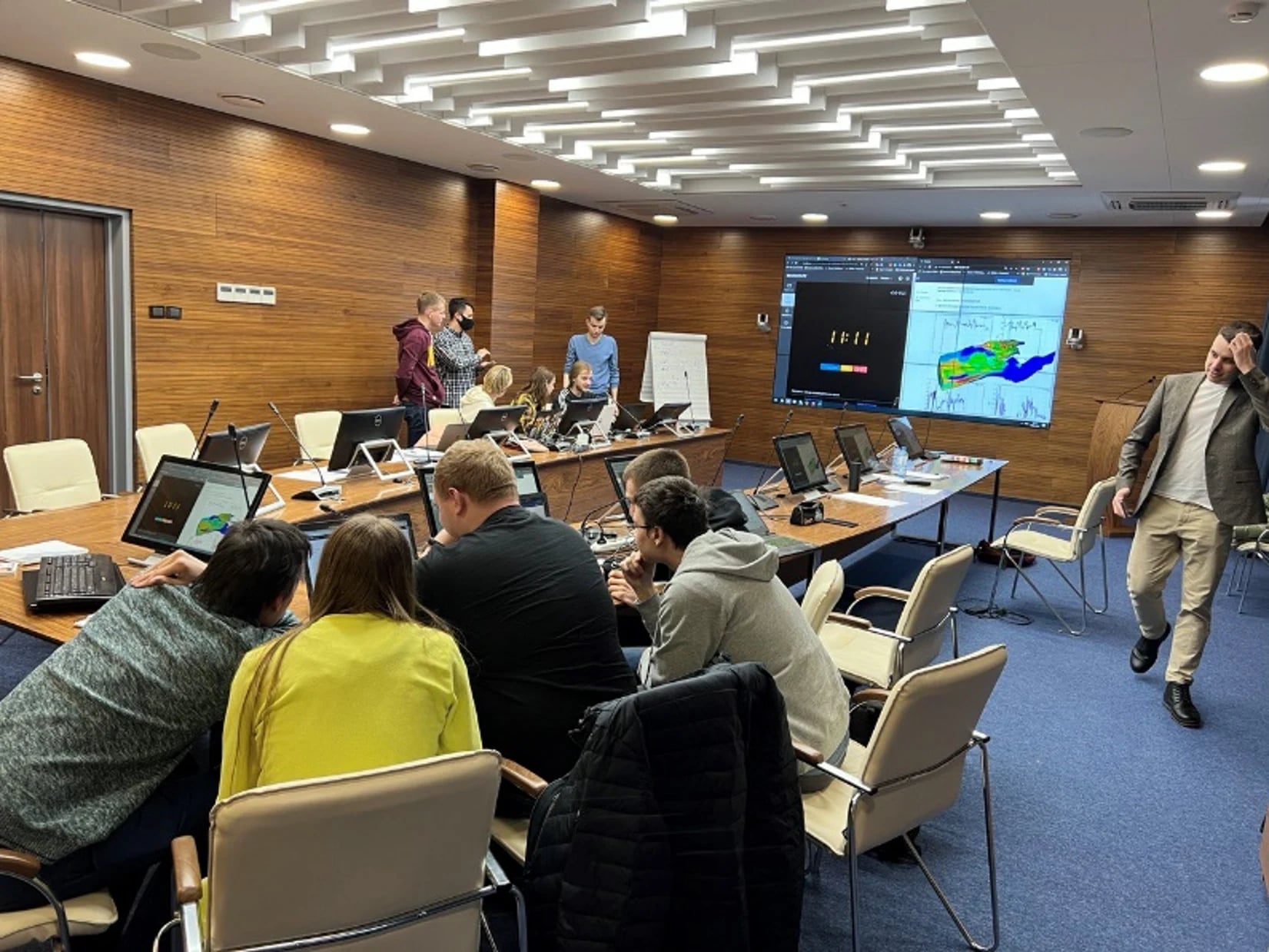 A course session: engineers at their laptops working through a calculation, with a map and charts on the screen